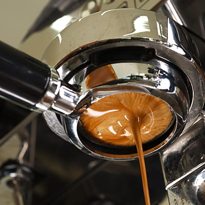 Close up of fresh espresso shot pouring out of machine.